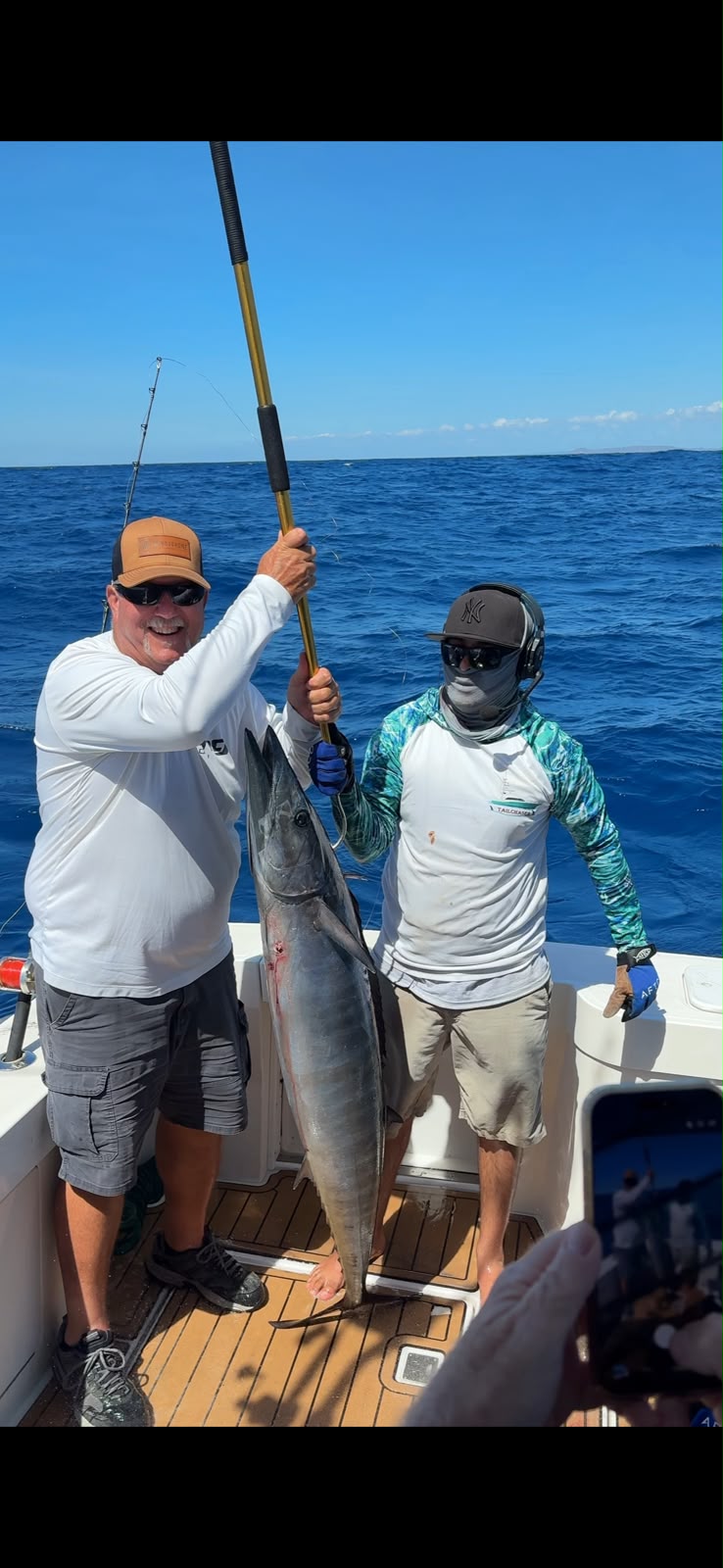 Two anglers with a wahoo aboard a sportfishing boat