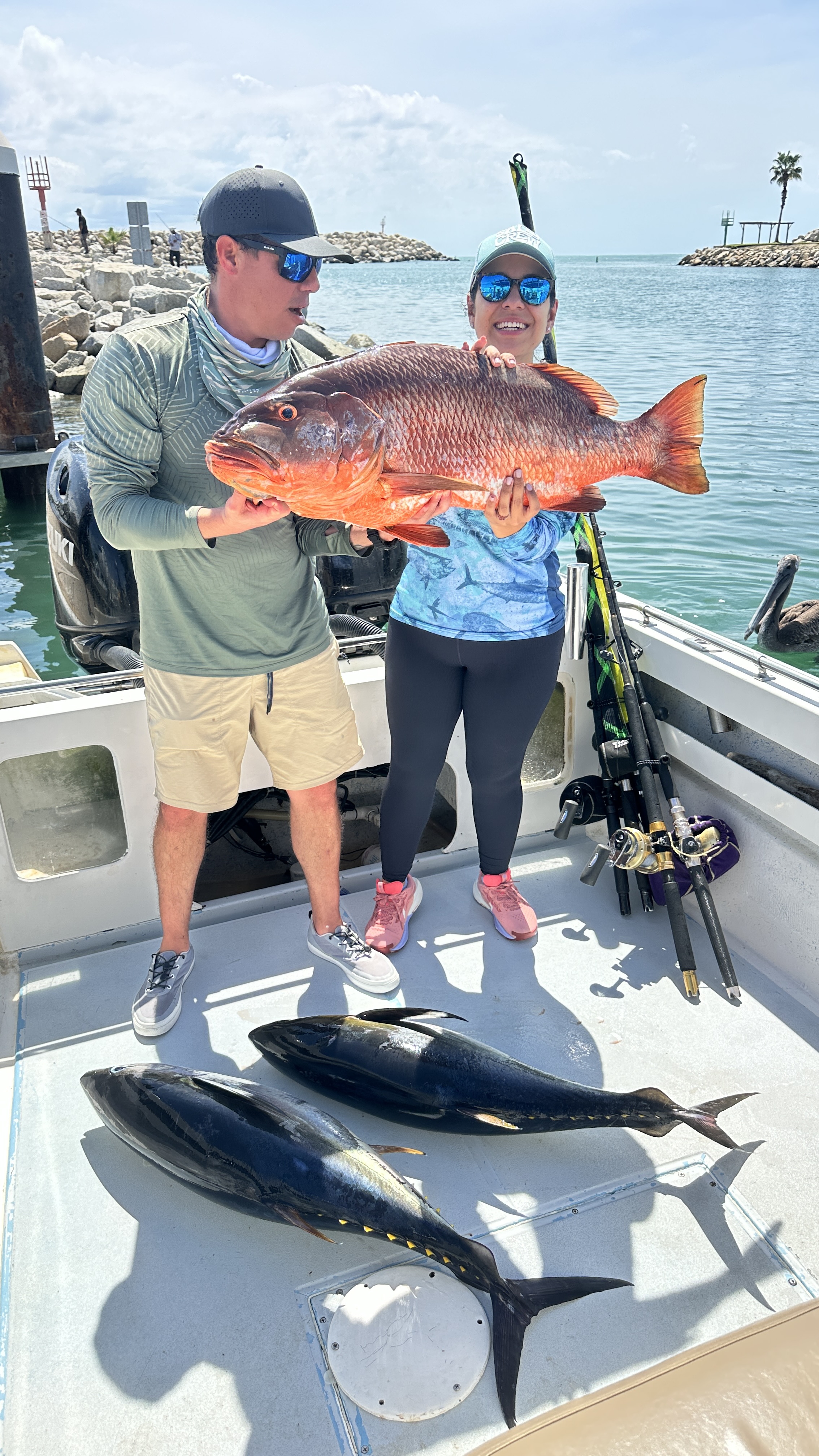 Anglers holding a snapper, with tuna on the deck